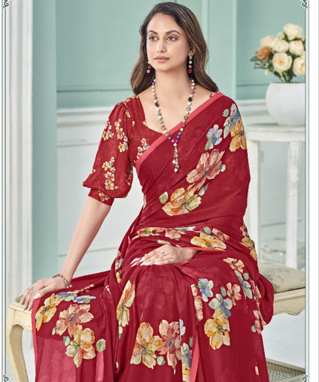 Woman wearing a red floral saree in a well-lit room with light blue walls.